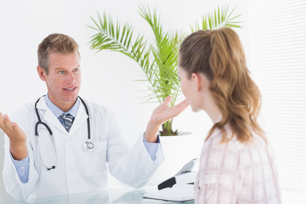 Happy doctor talking to patient in clinic