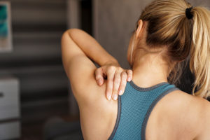 Athletic woman feeling pain in her neck and shoulder