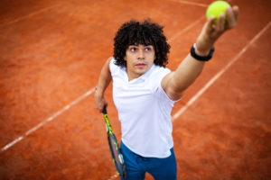 Young man serving tennis ball