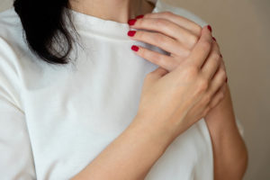 Close-up of woman in white T-shirt holding her painful wrist