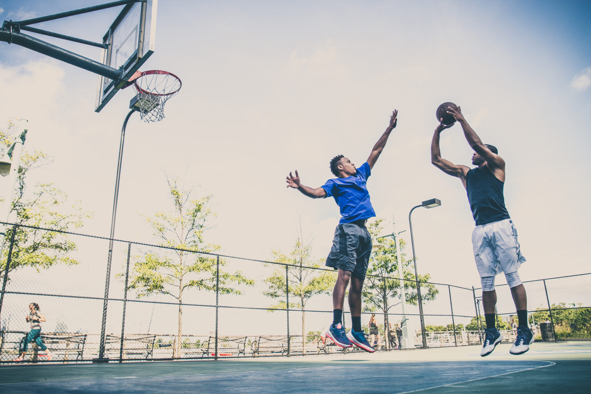 Two athletes playing basketball outdoors on court in New Jersey. Basketball is a common cause of ACL and Knee Meniscus injuries. These players have recovered from ACL and Knee Meniscus surgery