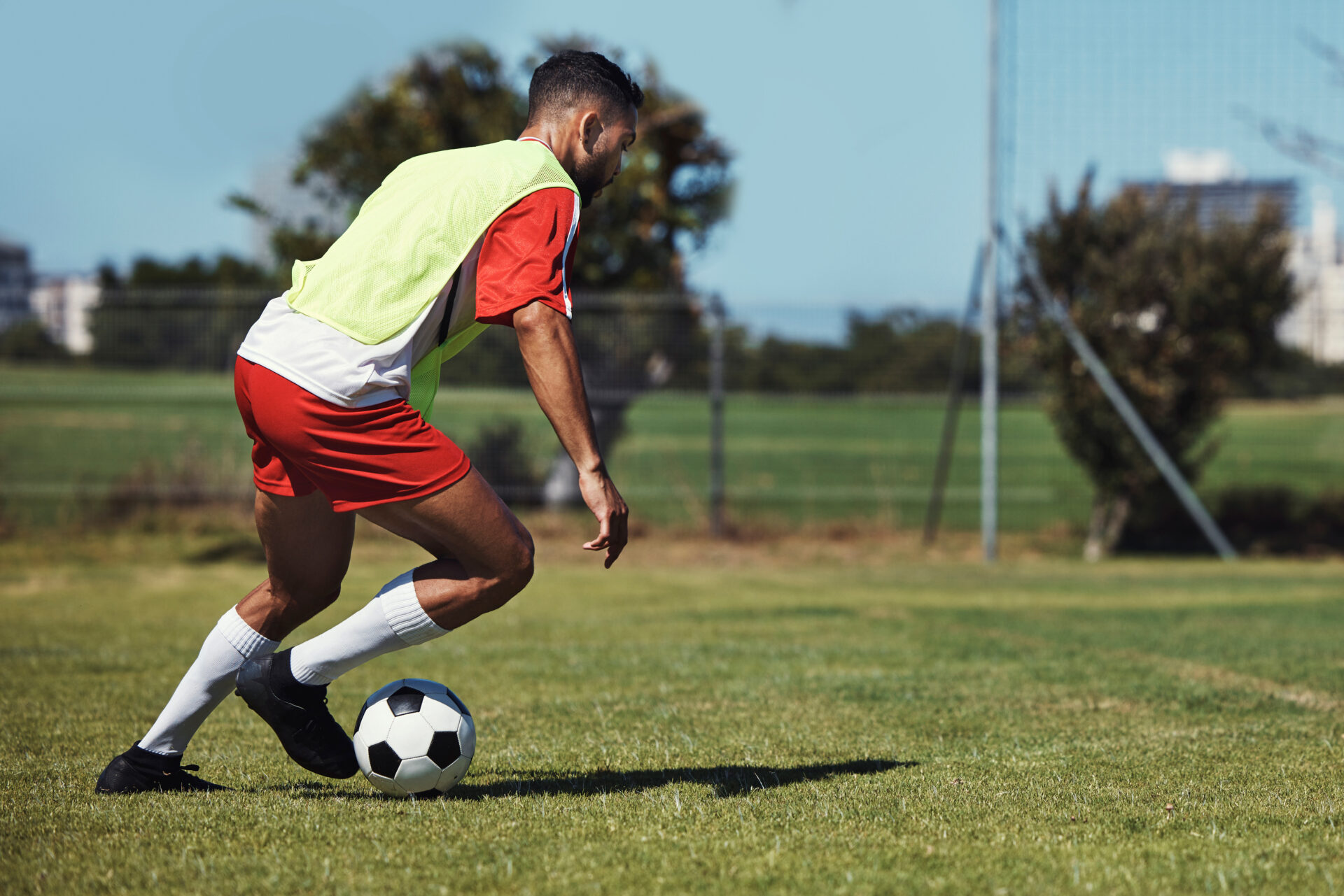 Male athlete is playing soccer on soccer field. Foot is planted while he switches directions - a movement that commonly results in knee meniscus and ACL injuries. This athlete is at risk for knee meniscus and ACL injuries. 