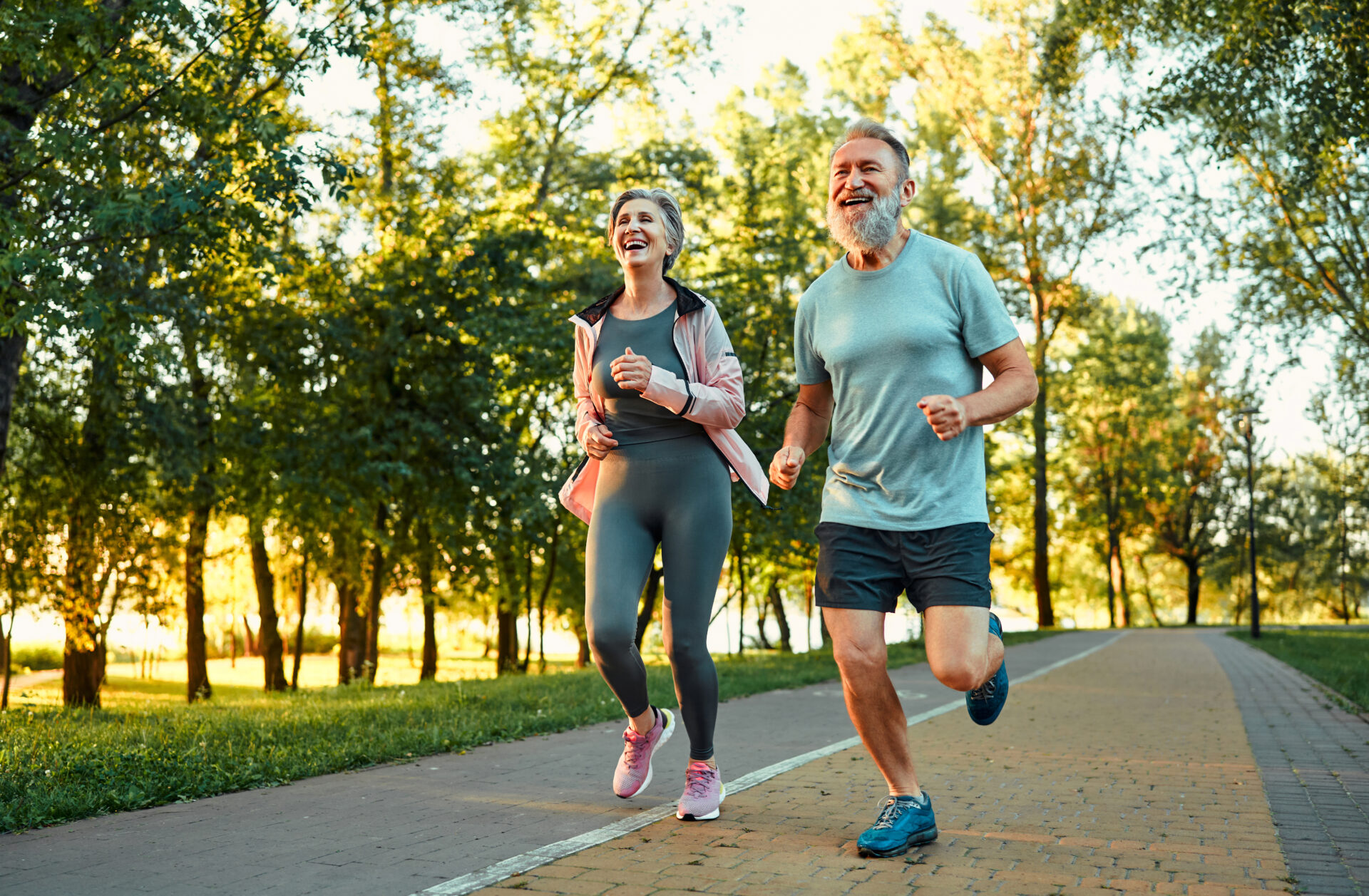 Caucasian elderly couple with sincere smile on faces enjoying outdoors cardio at green park. They both recovered from successful total knee replacement surgeries