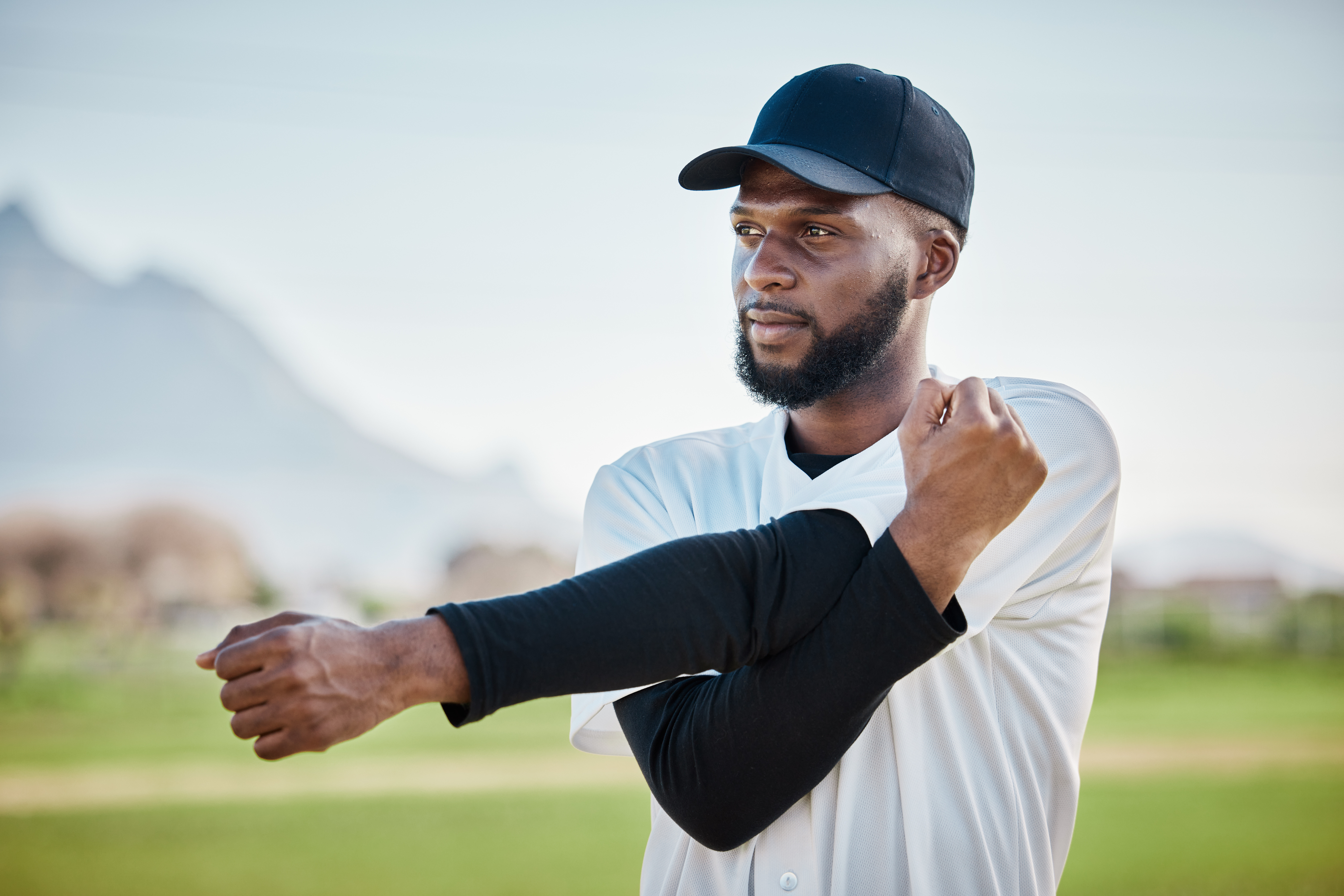 Baseball stadium, man on field stretching his arm muscles. Baseball player is stretching as part of his strength and conditioning program, he has recovered from shoulder and elbow injuries in baseball