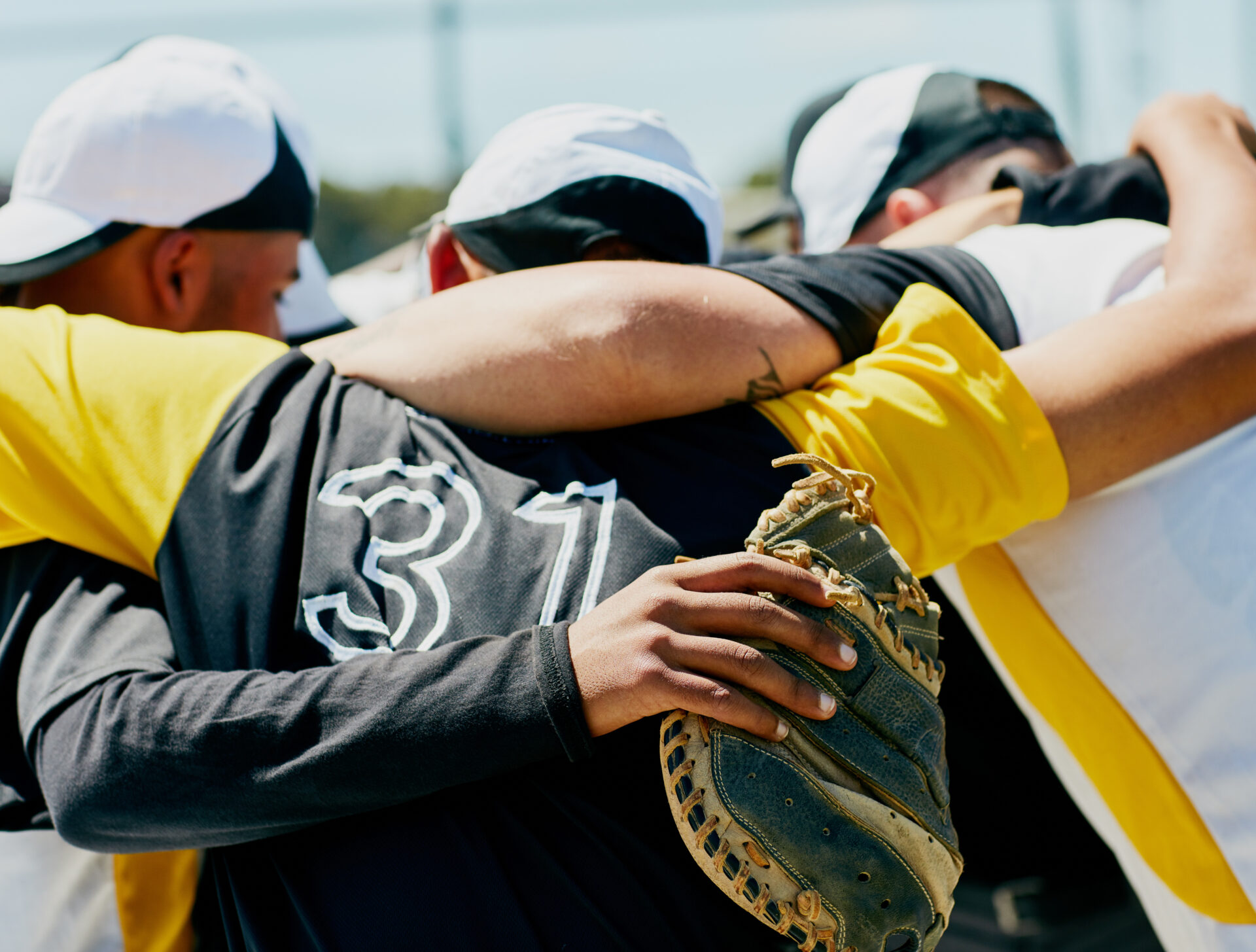 Cropped shot of a team of baseball players standing together in a huddle on the field