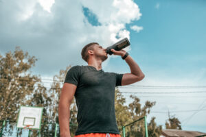 Athlete drinking water outdoors during summer exercise in hot weather