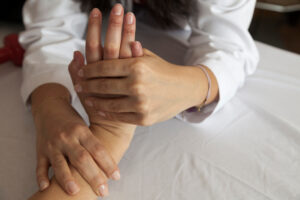 Woman stretching fingers and hand while experiencing hand arthritis stiffness and joint discomfort