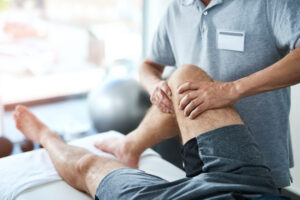 Physical therapist helping an adult perform a knee-strengthening exercise.