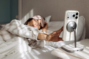 Adult reaching for a phone on a nightstand while experiencing stiff fingers in the morning